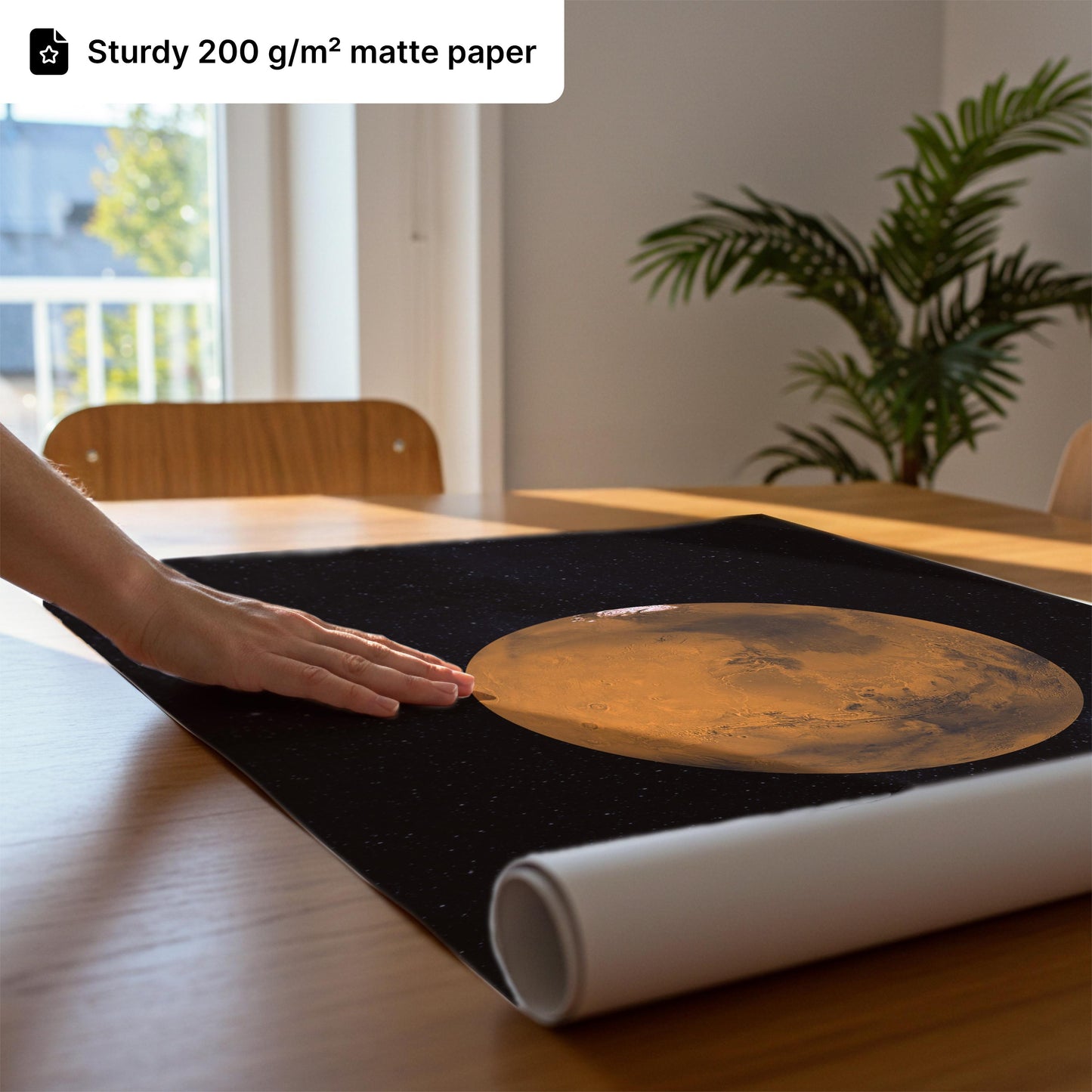 a hand resting on a black mat with a large, circular image of the moon on it, placed on a wooden table.