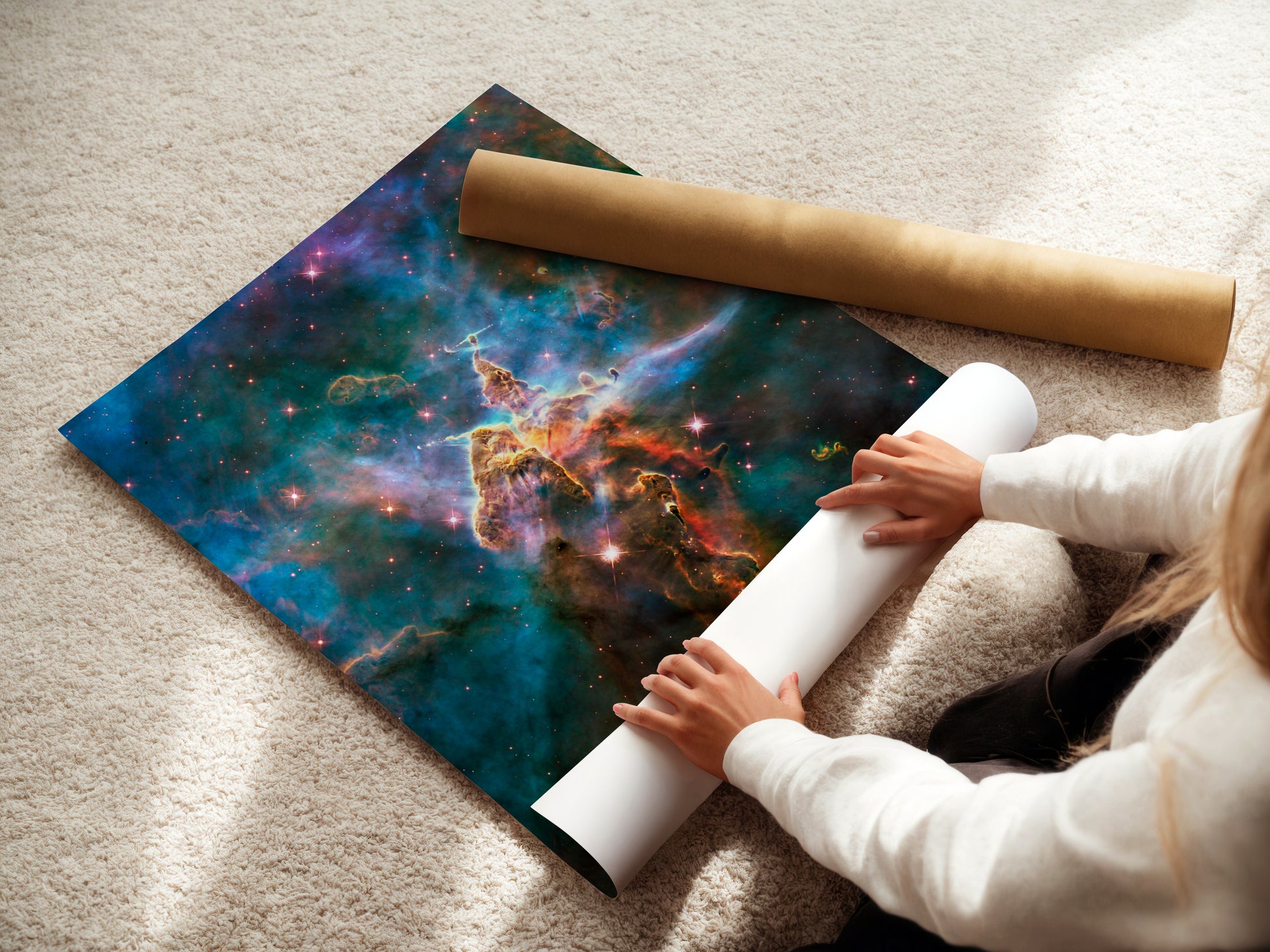 A person is holding a roll of paper and placing it on a large poster depicting a colorful, cosmic scene.