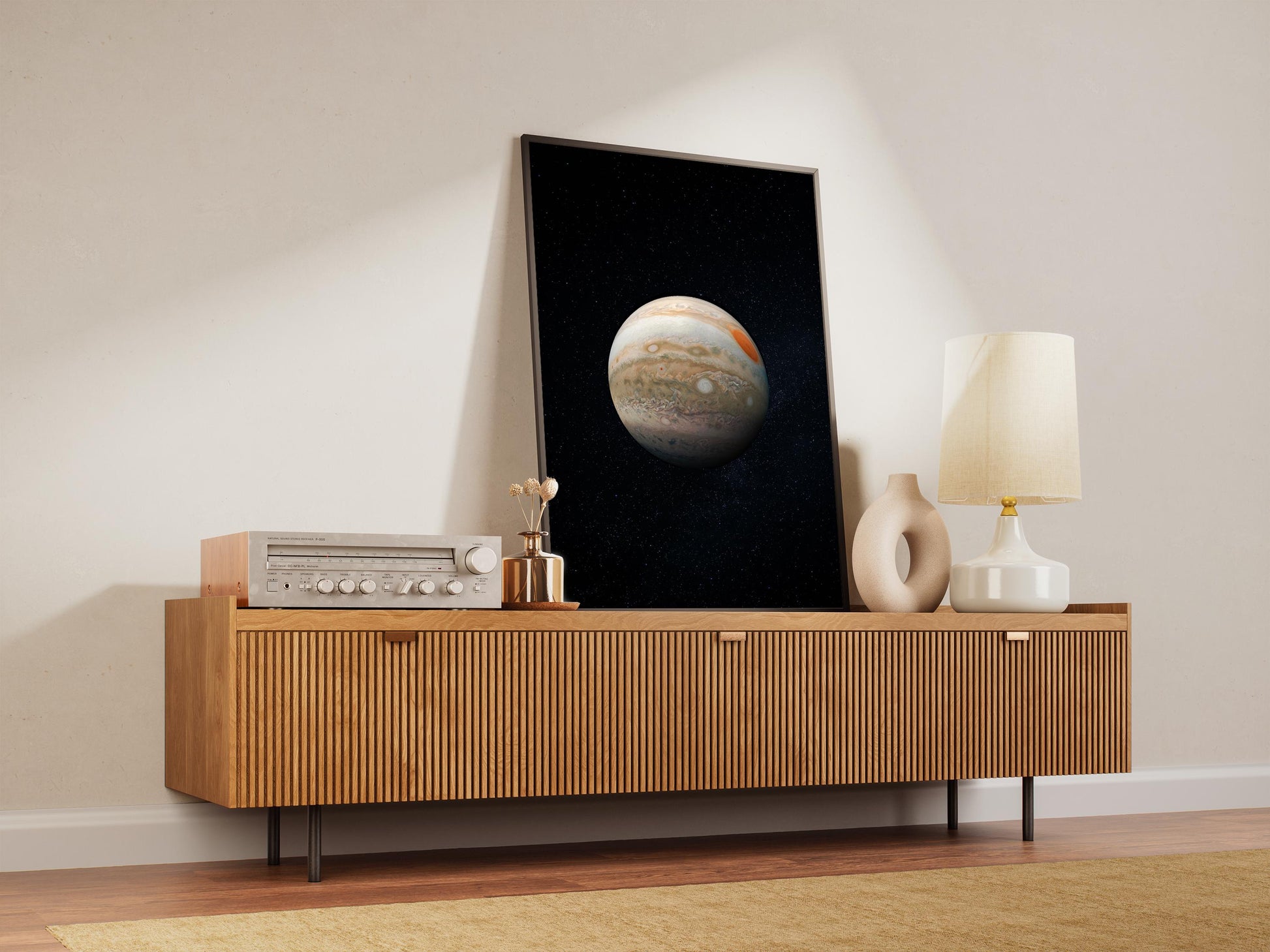 a wooden cabinet with a framed picture of a planet hanging on it, along with a lamp and other decorative items on the cabinet.