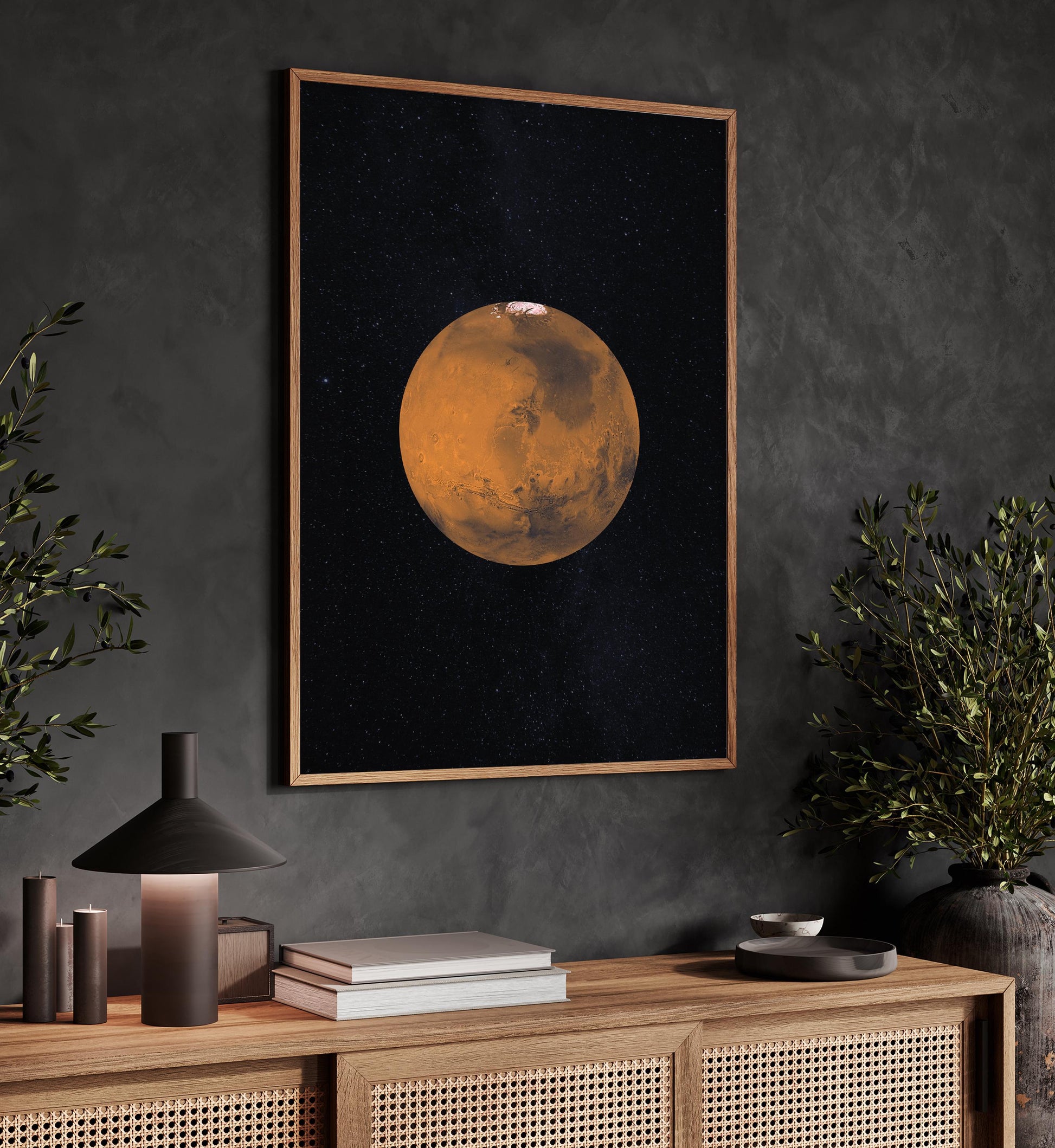 a framed poster of a planet, likely Mars, hanging on a wall above a wooden cabinet with various decorative items and plants.