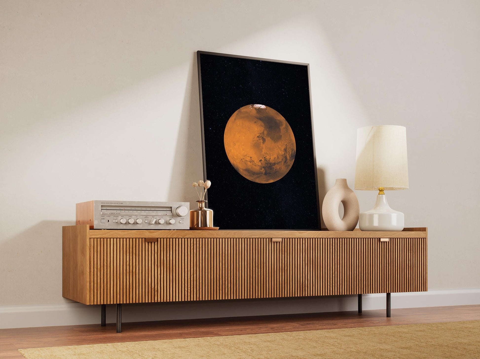 a wooden cabinet with a framed picture of a planet hanging on it, along with a lamp and other decorative items on the cabinet.