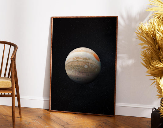 a large framed picture of the planet Jupiter against a black background, placed on a wooden floor next to a wooden chair.