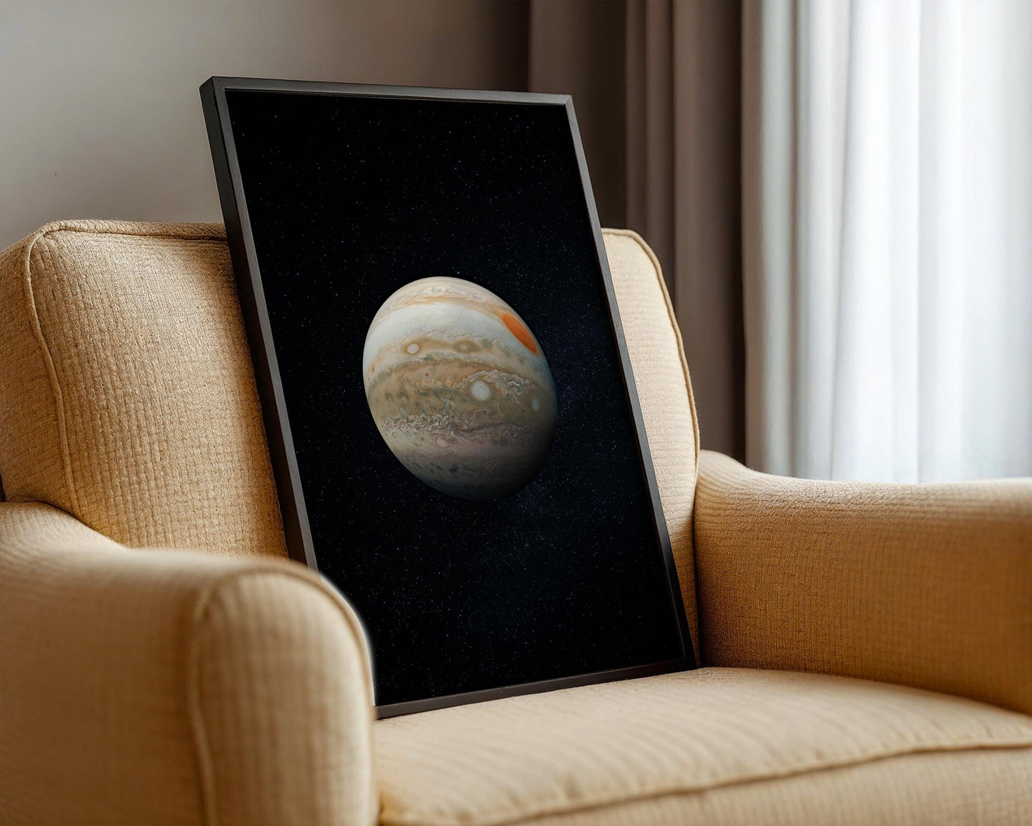 a framed picture of the planet Jupiter, which is displayed on the armrest of a beige armchair.