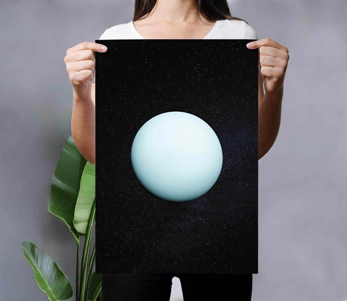 A woman holds a black poster with a white planet and starry background, creating a striking visual contrast.